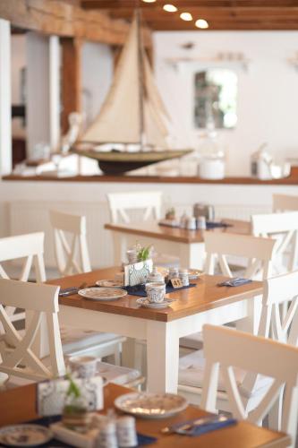 a table and chairs with a sail boat in the background at Hotel, Restaurant, Café Pharisäerhof - Nordseeurlaub mit Hund in Nordstrand
