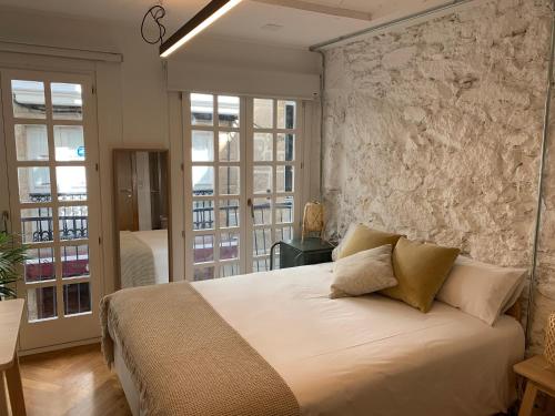 - une chambre avec un grand lit et un mur en pierre dans l'établissement Oktheway Coruña Historic Center, à La Corogne