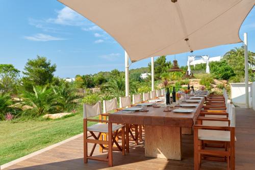 a long wooden table with chairs and an umbrella at Fiframar in Sant Josep de Sa Talaia