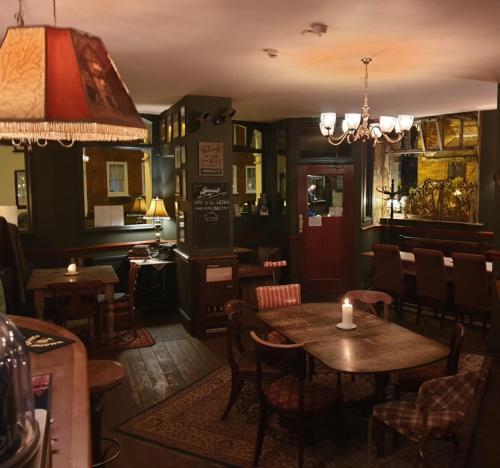 un restaurant avec des tables et des chaises et un lustre dans l'établissement The Olde Swan Hotel, à Chertsey