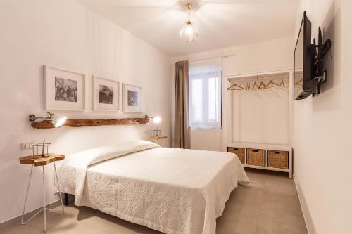 een witte slaapkamer met een bed en een raam bij Elune B&B in Baunei