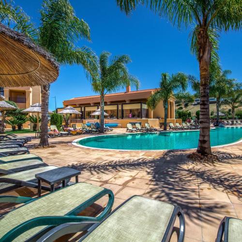 a swimming pool with chaise lounge chairs and palm trees at Luz Beach Luxury Apartment in Luz