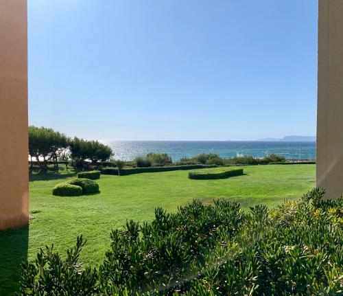 a view of a lawn with the ocean in the background at Domaine de La Coudouliere, Vue Mer, Plage, Piscine et Parc in Six-Fours-les-Plages