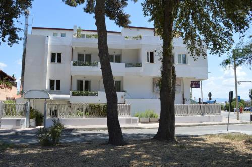 a white building with trees in front of it at Hotel Chentu Lunas in Cagliari