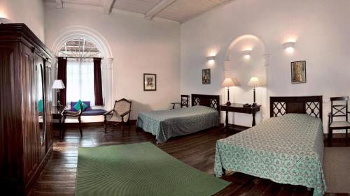 een kamer met 2 bedden en een tafel en stoelen bij Neemrana's- Tower House in Cochin