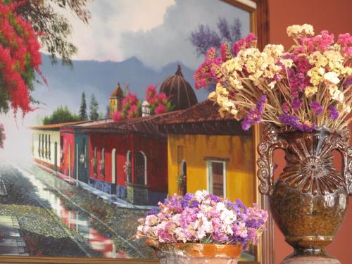 a vase filled with flowers sitting next to a painting at 7 orejas in Quetzaltenango