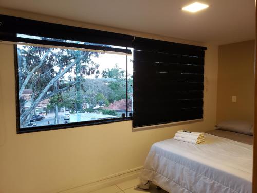 ein Schlafzimmer mit einem Fenster mit einem Bett und einer Aussicht in der Unterkunft Búzios Loft charmoso in Búzios