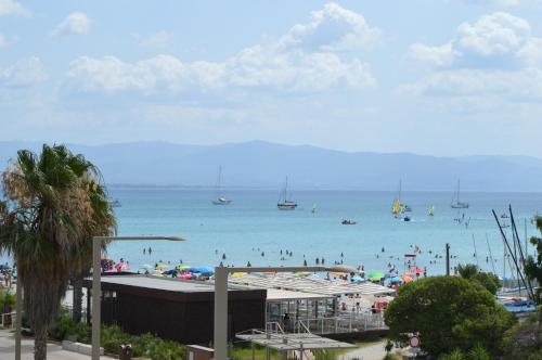 a beach with people in the water and boats at Hotel Chentu Lunas in Cagliari