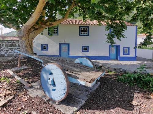 a wooden bench under a tree in front of a building at Casas Dos Vimes in Fajã dos Vimes