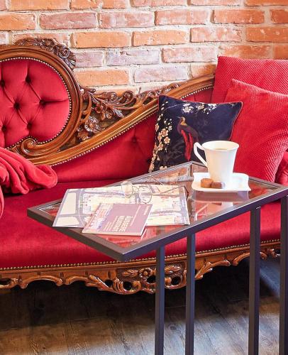 a glass table with a coffee cup on a red couch at Strohhutmanufaktur in Dresden
