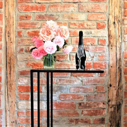 a table with a bottle of wine and flowers on it at Strohhutmanufaktur in Dresden