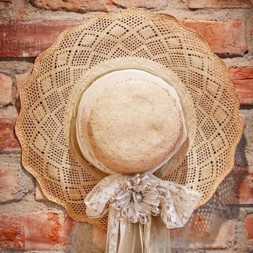 a straw hat hanging on a brick wall at Strohhutmanufaktur in Dresden
