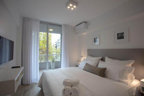 Un dormitorio blanco con una cama grande y una ventana en BAIRES HOMES PALERMO III en Buenos Aires