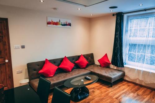 a living room with a brown couch with red pillows at Hotel Quality Stay,2 bed Apartment near the City Centre, 2min Walk from Metro Station in London