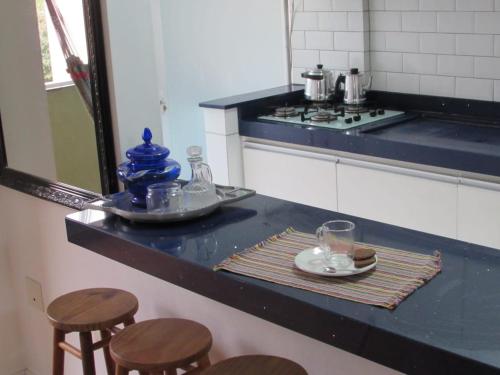 a kitchen with a counter with stools and a plate and glasses at Apê da Gabi in Balneário Camboriú