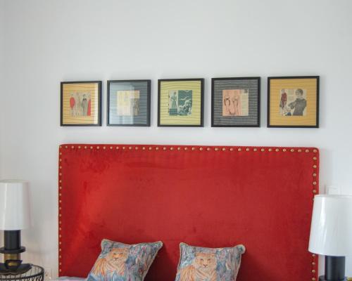 a row of pictures on a wall above a red headboard at Casa Brazao Mira in Casa Branca