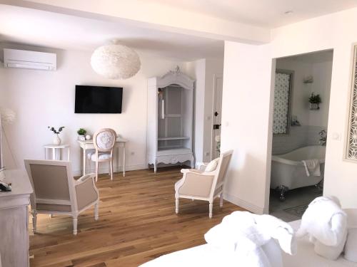 Cette chambre blanche dispose de chaises, d'une table et d'une baignoire. dans l'établissement Le Cœur de la Bastide - Adult only, à Carcassonne