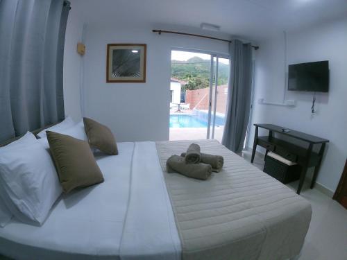 a bedroom with a bed with a teddy bear on it at Hotel Plein Soleil in Grand Anse