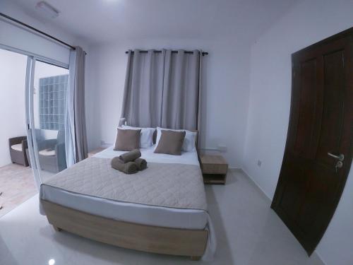 a bedroom with a bed with a teddy bear on it at Hotel Plein Soleil in Grand Anse