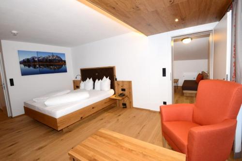 a bedroom with a bed and a chair and a table at Hotel Park in Sankt Johann in Tirol