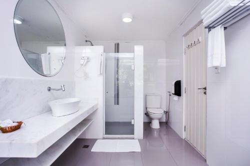 a white bathroom with a sink and a mirror at Hotel Ilhabela in Ilhabela