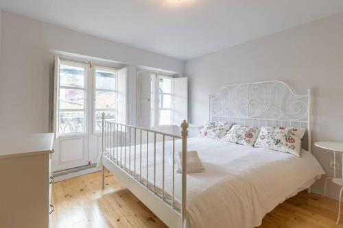 een witte slaapkamer met een wit bed en een raam bij Heart Of The Porto in Porto