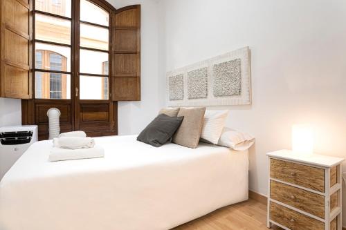 Un dormitorio blanco con una cama grande y una ventana en Livemalaga Clemens, en Málaga