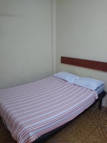 een kleine slaapkamer met een bed met een gestreepte deken bij Hotel Santo Domingo in Tuxtla Gutiérrez