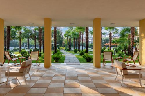 um átrio no resort com cadeiras e palmeiras em Hotel Savoia Thermae & SPA em Abano Terme