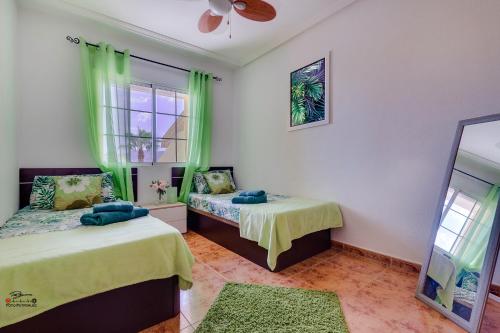 two beds in a room with green curtains and a mirror at Apartamento Havana in Los Nietos