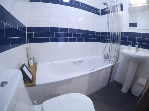 a bathroom with a tub and a toilet and a sink at St Columba Hotel in Iona