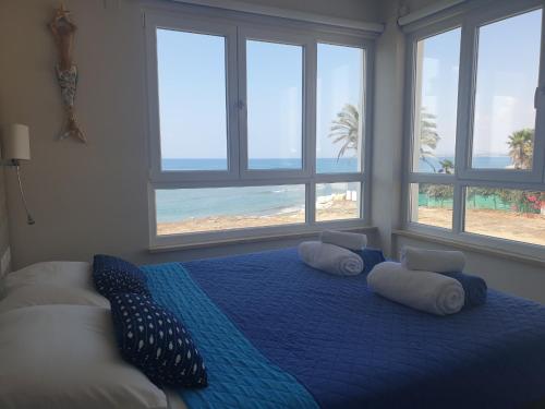 a bedroom with a blue bed with pillows and a beach at Periyiali Beach Sunset Suite A7 in Pervolia