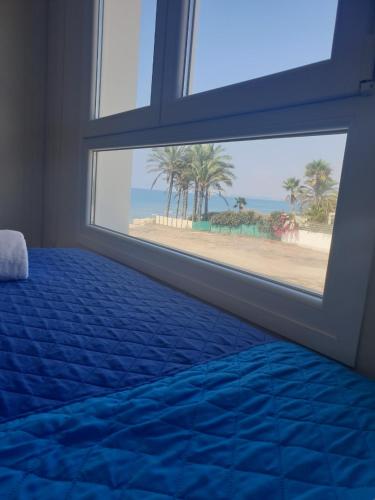 a bedroom with a window with a view of the beach at Periyiali Beach Sunset Suite A7 in Pervolia