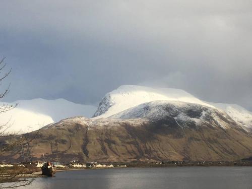 a snow covered mountain next to a body of water at situated at the heart of fort william in Fort William