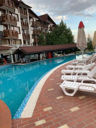 eine Reihe von weißen Liegestühlen neben einem Pool in der Unterkunft Belvedere Holiday Club ...VIP ap. in Bansko