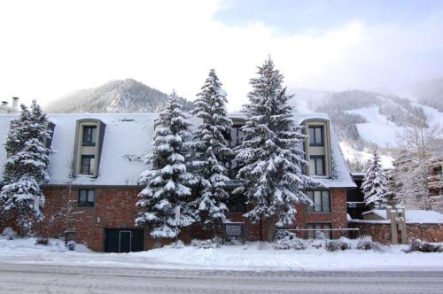 a building with snow covered trees in front of it at Chateau Dumont Unit 10, Centrally Located Condo, 1 Block from the Gondola in Aspen