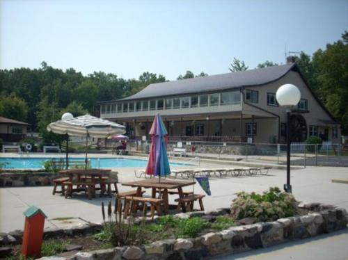 a pool with tables and umbrellas in front of a building at Round Top Loft Cottage 2 in Gettysburg