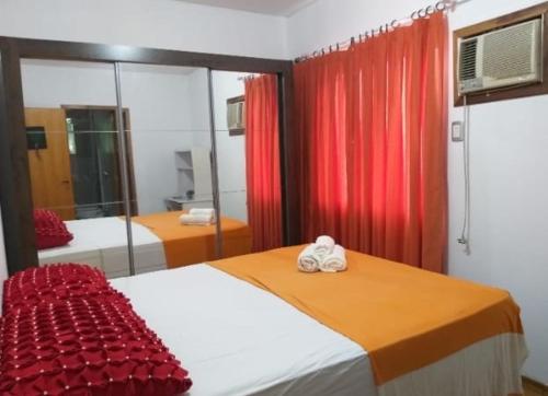 a bedroom with two beds and a red curtain at Pousada Domiciliar Agua Verde in Jaraguá do Sul