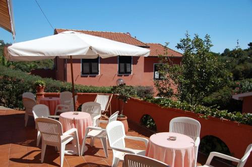 a patio with tables and chairs and a white umbrella at Residence Villa Franca in Capoliveri