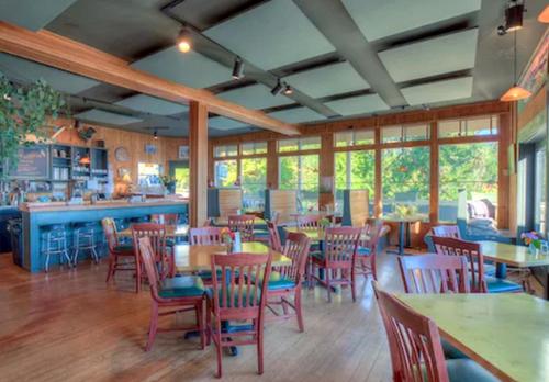 um restaurante com mesas e cadeiras de madeira e janelas em Kingfish at West Sound em Eastsound