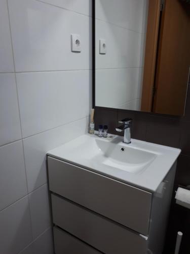 ein Badezimmer mit einem weißen Waschbecken und einem Spiegel in der Unterkunft Coimbra Holiday Residence in Coimbra