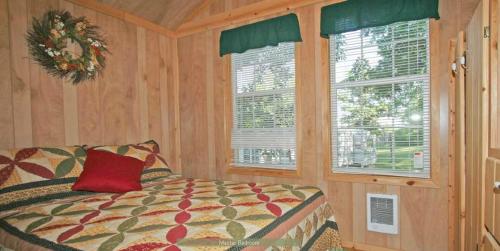 a bedroom with a bed with a red pillow and two windows at Round Top Premiere Cottage 6 in Gettysburg