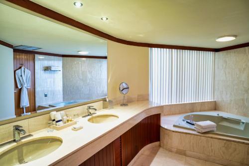 a bathroom with two sinks and a tub and a mirror at Hotel Estelar Miraflores in Lima