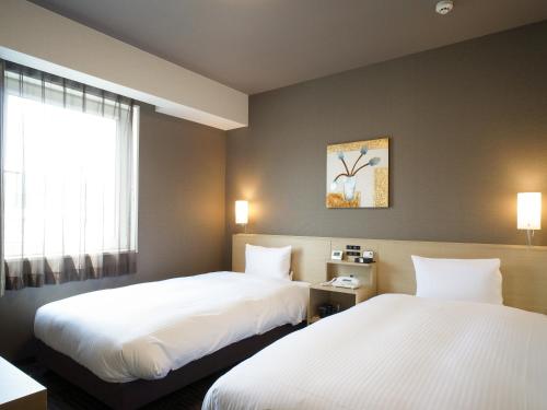 Hotel Route Inn Ofunato في Ōfunato: غرفة فندقية بسريرين ونافذة