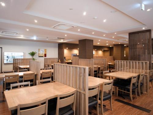 a dining room with wooden tables and chairs at Hotel Route Inn Ofunato in Ōfunato