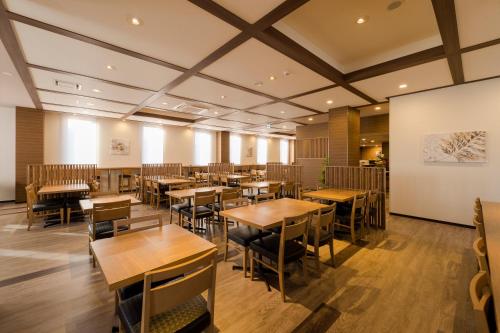 a dining room with wooden tables and chairs at Hotel Route-inn Utsunomiya Yuinomori -Lightline Yuinomori Nishi Ekimae- in Utsunomiya