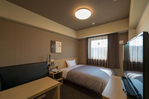 a hotel room with a bed and a window at Hotel Route-inn Utsunomiya Yuinomori -Lightline Yuinomori Nishi- in Utsunomiya
