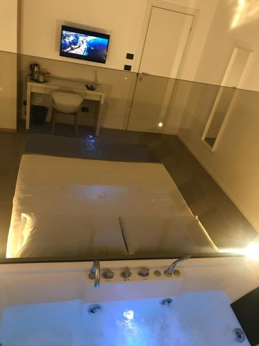 a room with a tub and a tv and a table at Le Dimore Degli Archi Catania in Catania