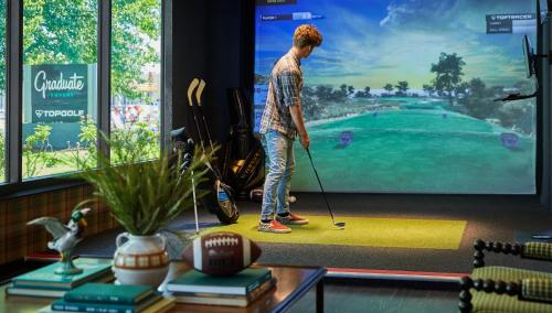 a man is playing golf on a tv screen at Graduate by Hilton Eugene in Eugene
