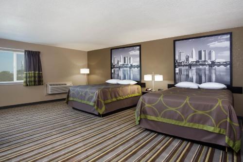 two beds in a hotel room with two windows at Travel Inn Of Sidney Ohio in Sidney